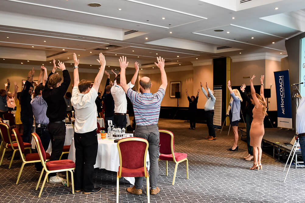 Attendees with hands raised during an interactive workshop session at Growth Club